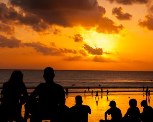 People are silhouetted against the sunset over Kuta Beach